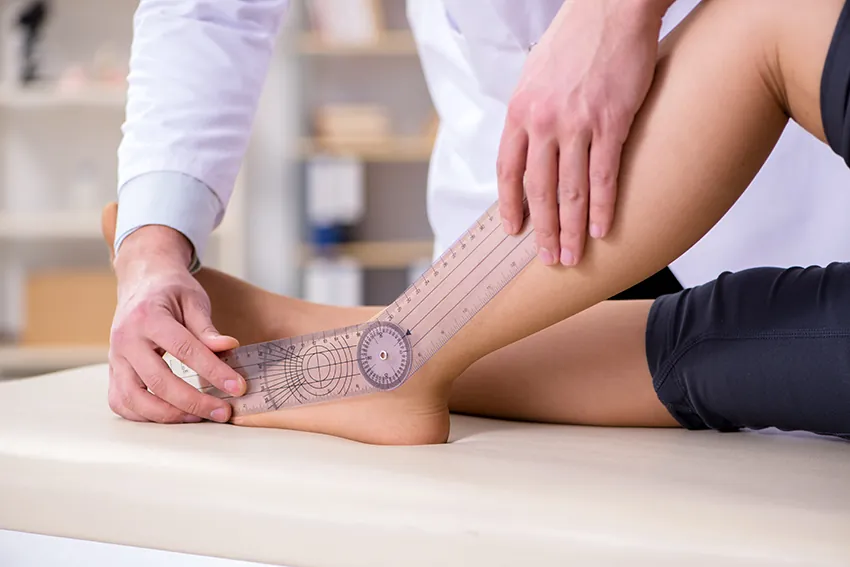 Physiotherapeut misst mit einem Goniometer die Beweglichkeit des Sprunggelenks – Physiotherapie in Graz