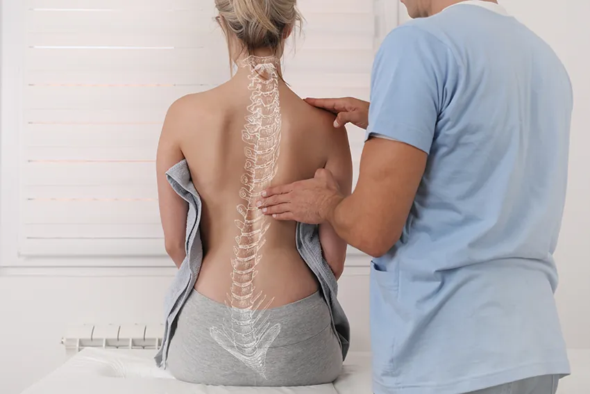 Skoliosetherapie nach Schroth: Therapeut untersucht die seitlich gekrümmte Wirbelsäule einer Patientin
